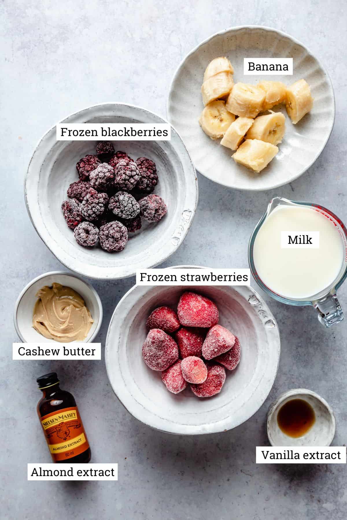 Ingredients for smoothie in various bowls and a jug.