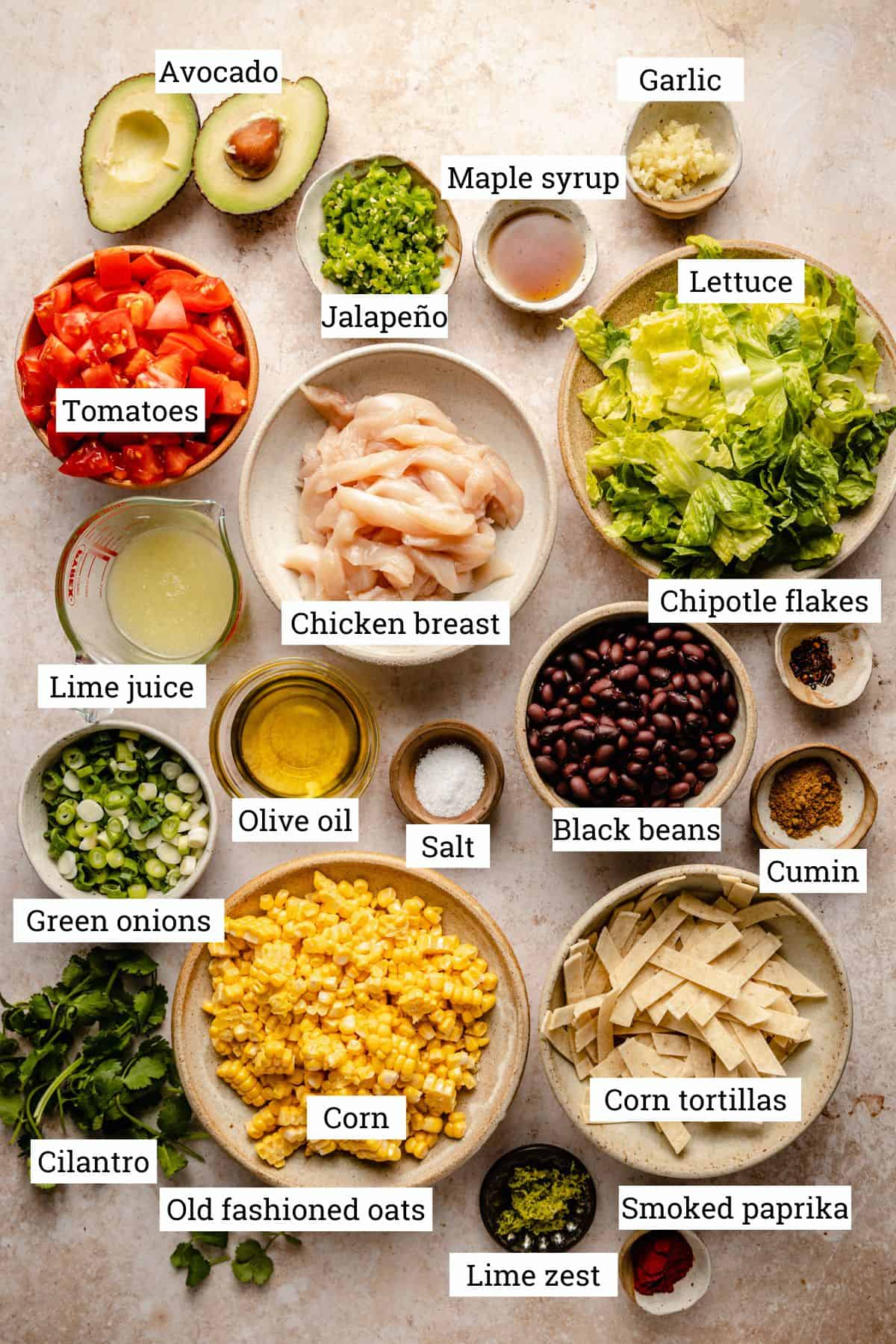 Ingredients in various bowls including, black beans, chicken, corn and corn tortilla strips.