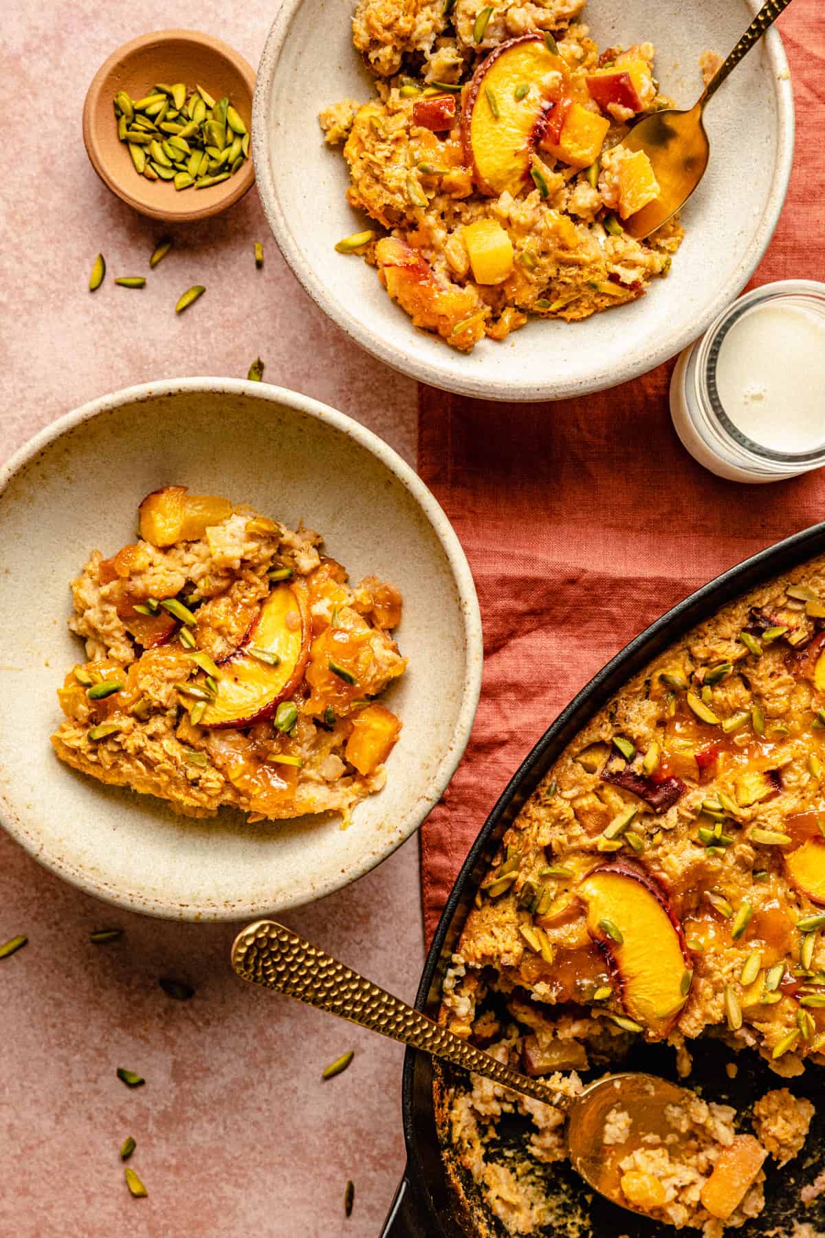 Two bowls of baked oatmeal served up with the baking dish with a spoon in.