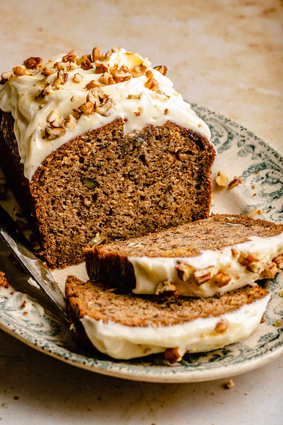 Banana Pecan Bread on a platter with a few slices cut showing the insides.