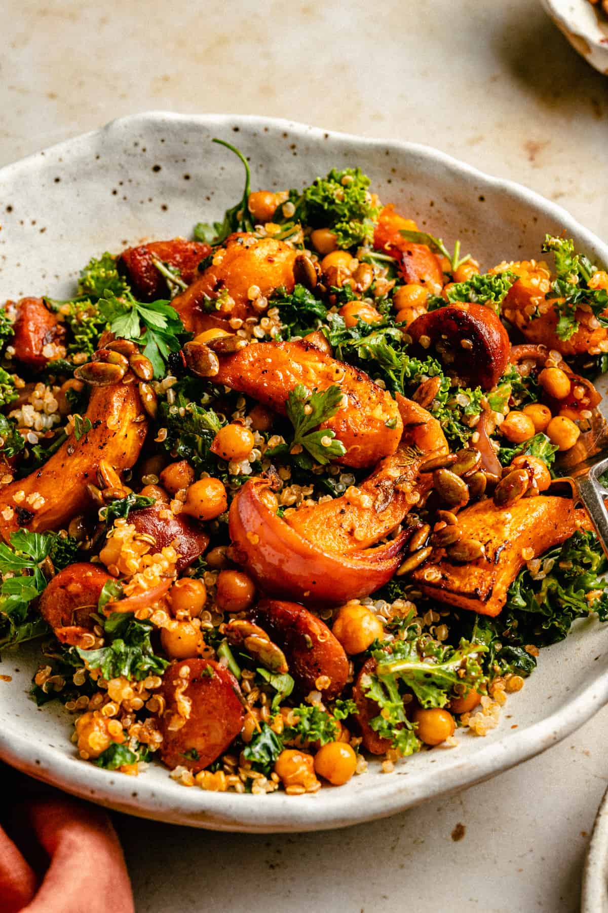 Close up of roast pumpkin salad in a bowl showing the vegetables and quinoa with a fork to the side.