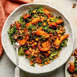 Roast pumpkin salad with chorizo served in a cream bowl with a fork and a napkin to the side.