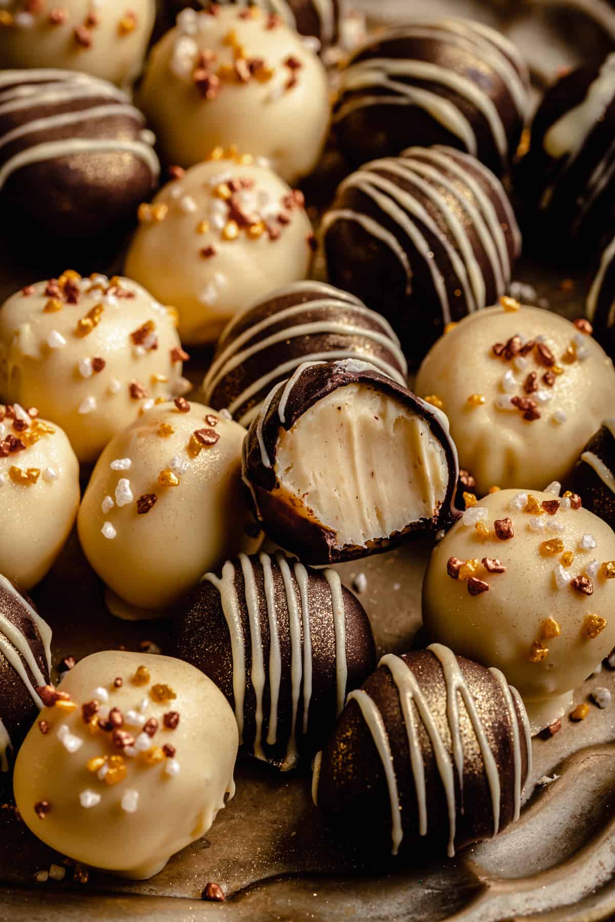 A close up of a white chocolate truffle on bitten on top of the others on a platter.