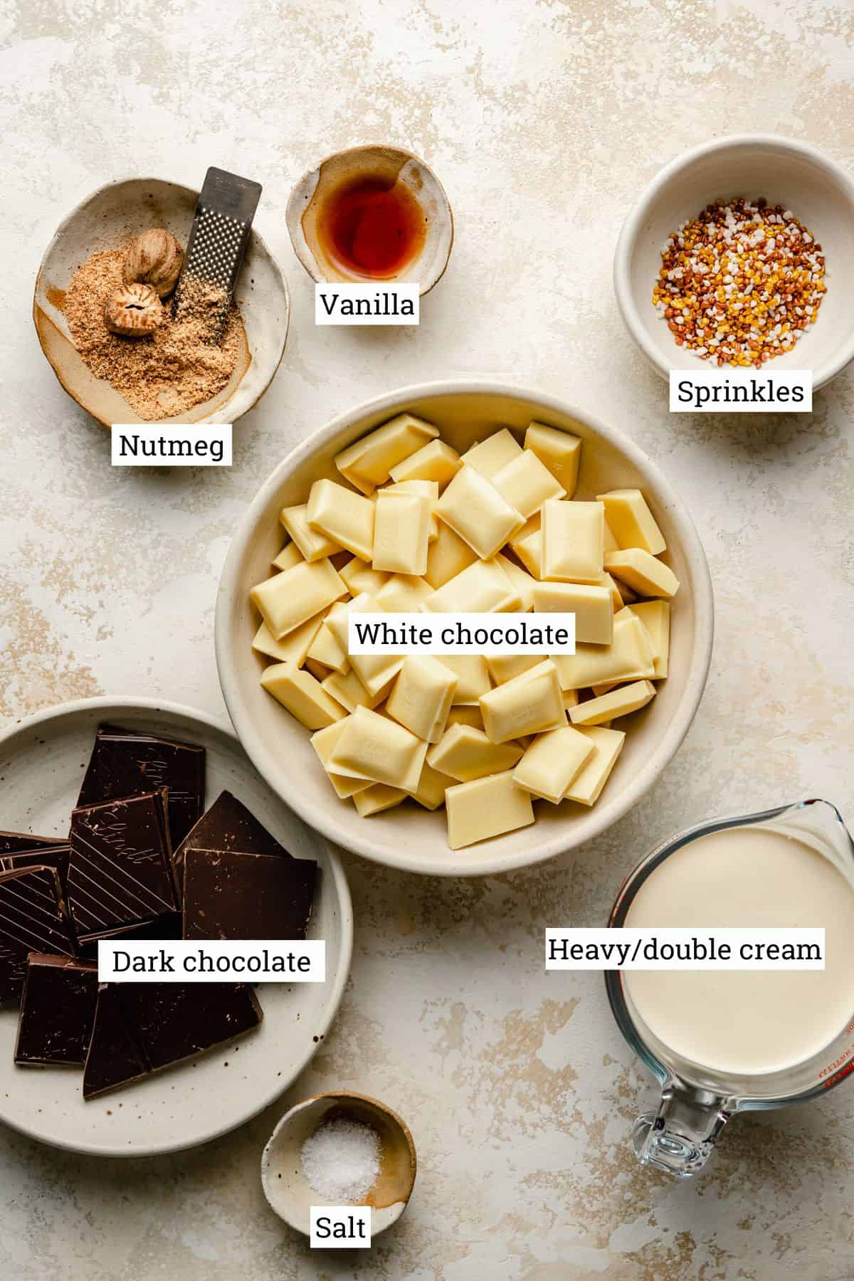 Ingredients in bowls for chocolate truffles, including white chocolate, cream, nutmeg and vanilla.