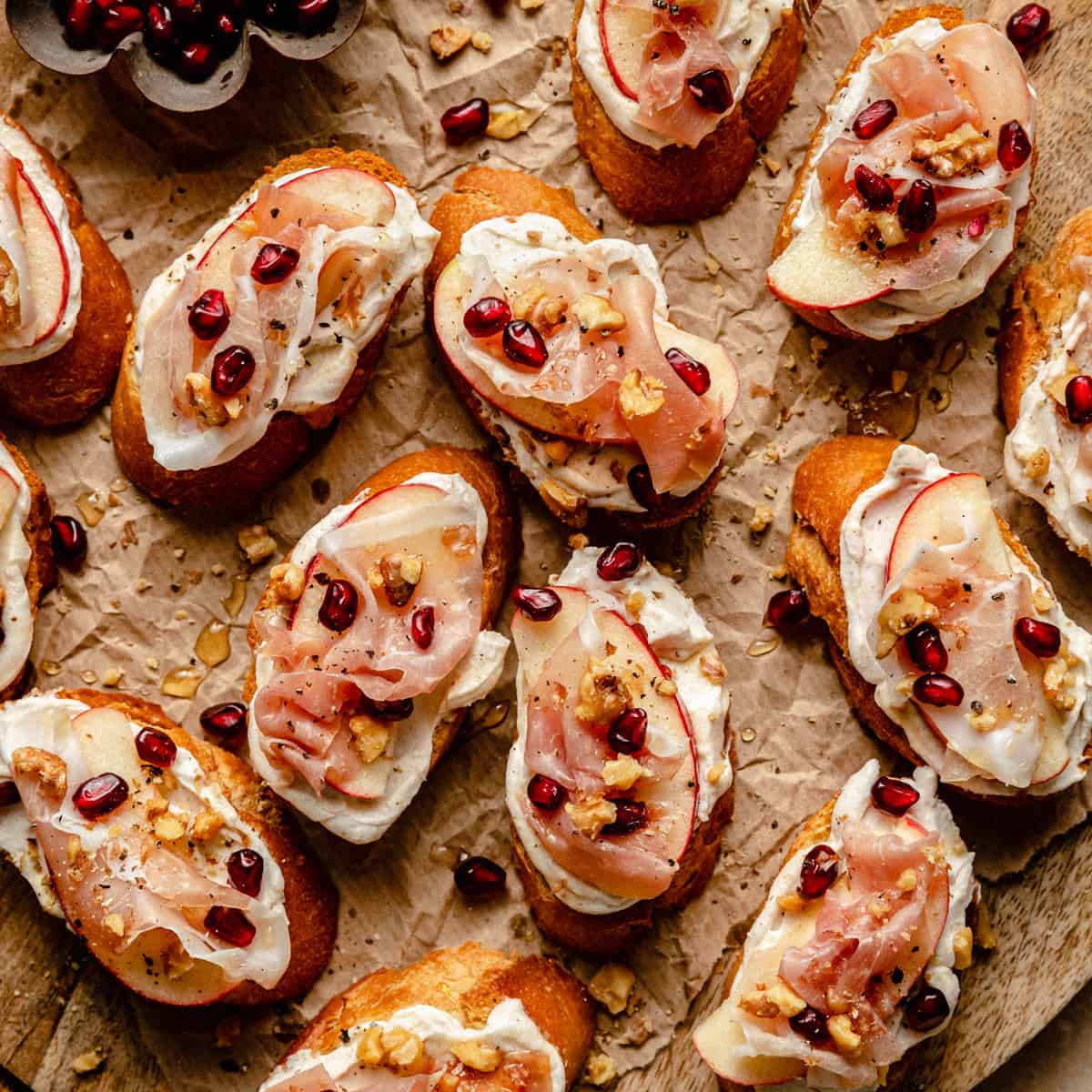 An array of ricotta crostini on a board with various toppings over the top. 