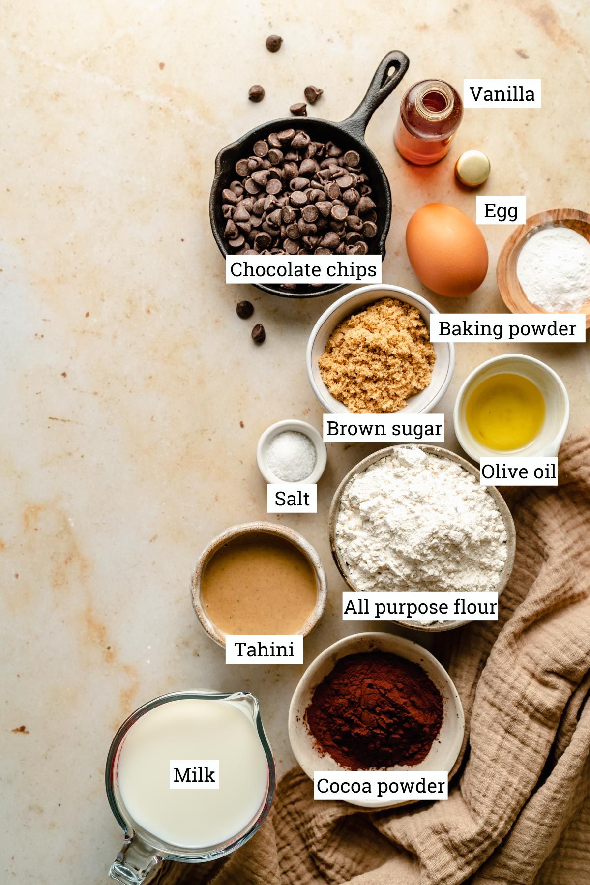 Array of ingredients for drop pancakes in various bowls including cocoa powder.