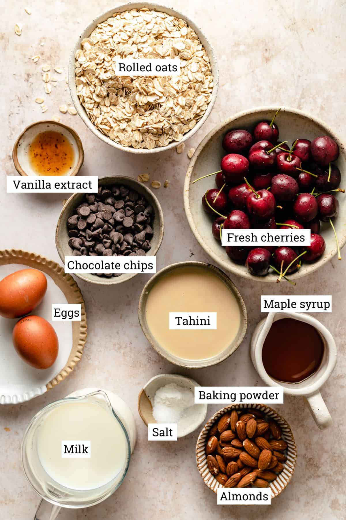 Ingredients for the chocolate chip baked oatmeal with cherries in various bowls on work surface.