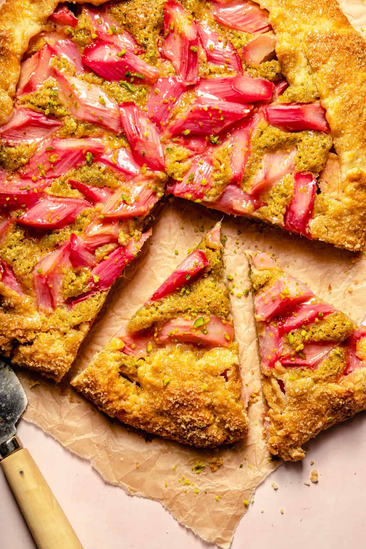 Rhubarb galette cut into wedges on brown parchment paper.