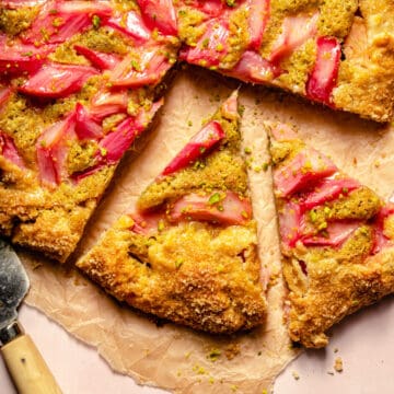 Rhubarb galette on brown parchment cut into wedges with a knife to the edge.