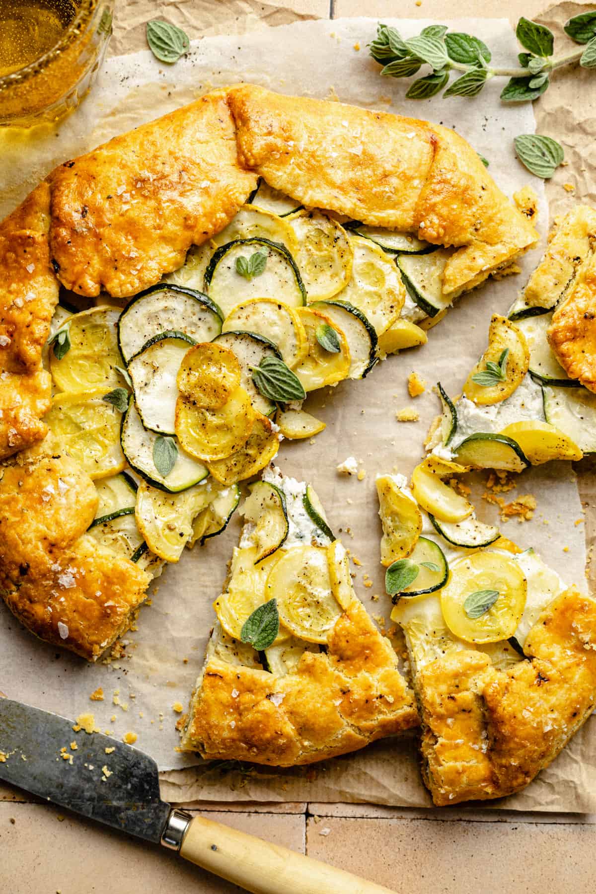 A couple of wedges of zucchini galette arranged on parchment with a knife.